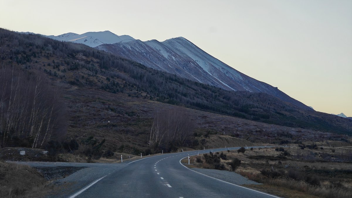Road curving through dark hills at dusk with