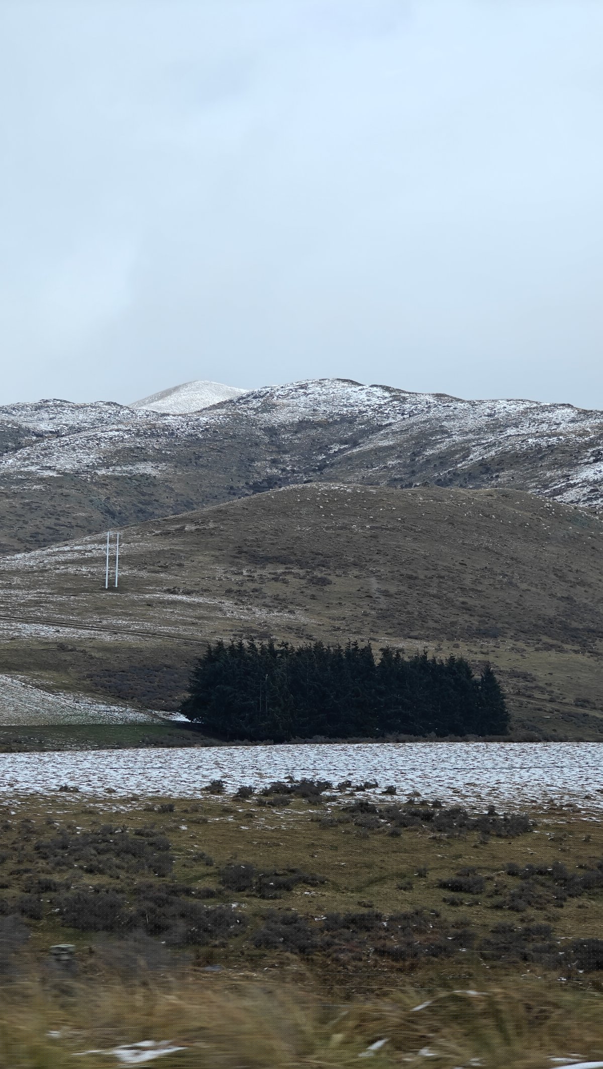 Rolling high-country hills patched with snow, a small