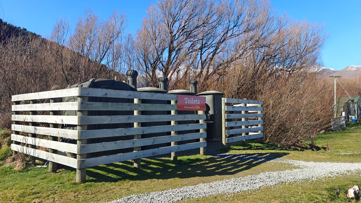 Rustic timber-slat screen fencing the property's composting toilet