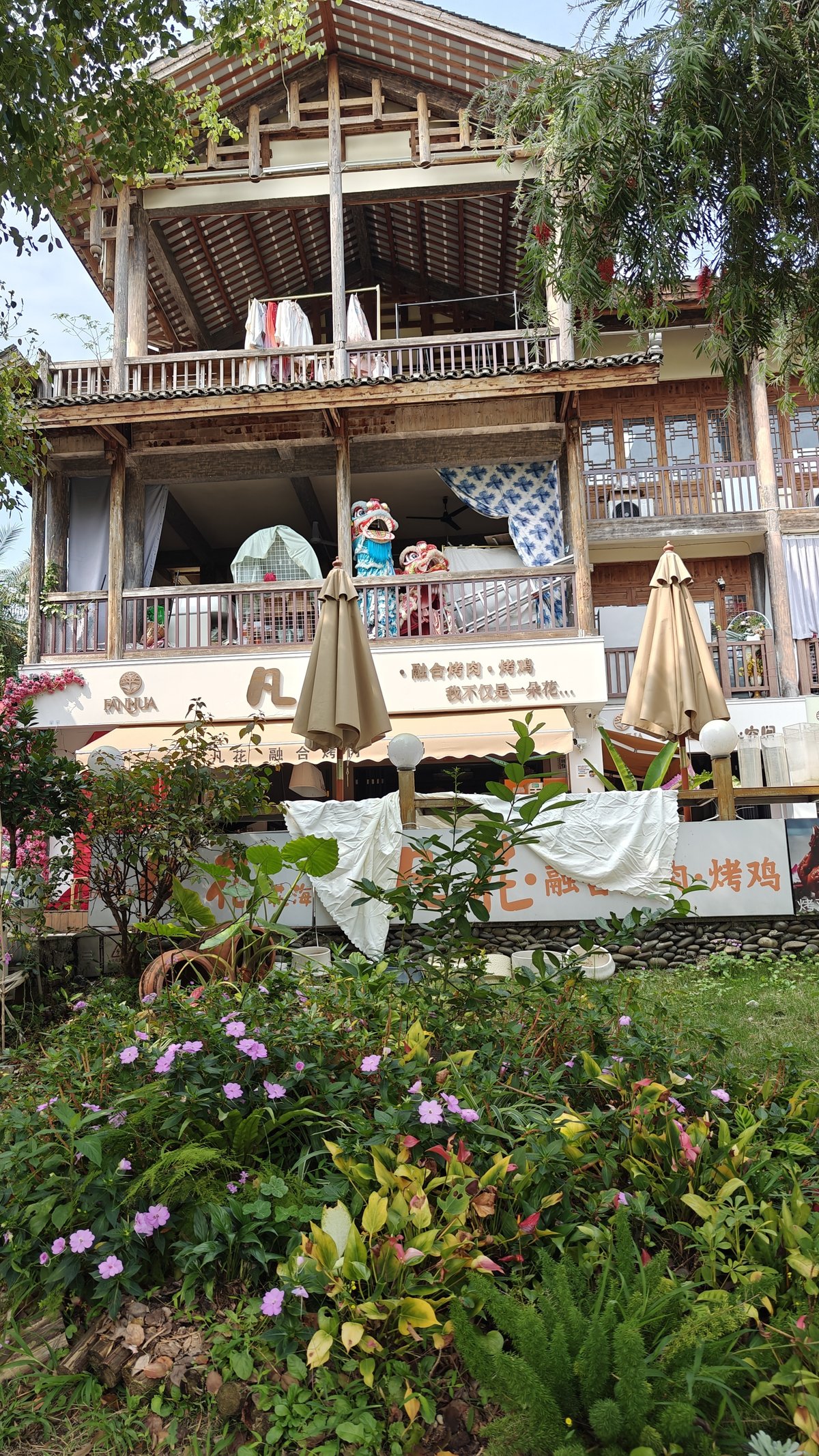 Rustic wooden café/restaurant with umbrella seating, flowers in