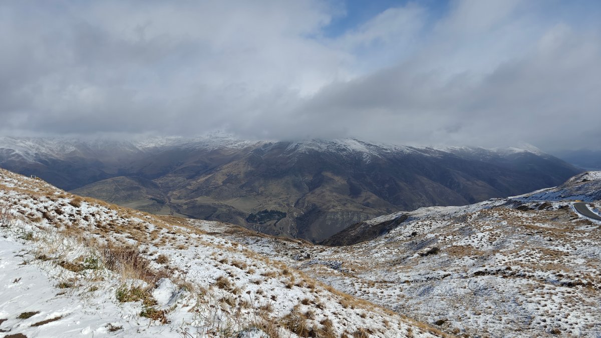 Snow-covered mountainside under a bright sky with drifting