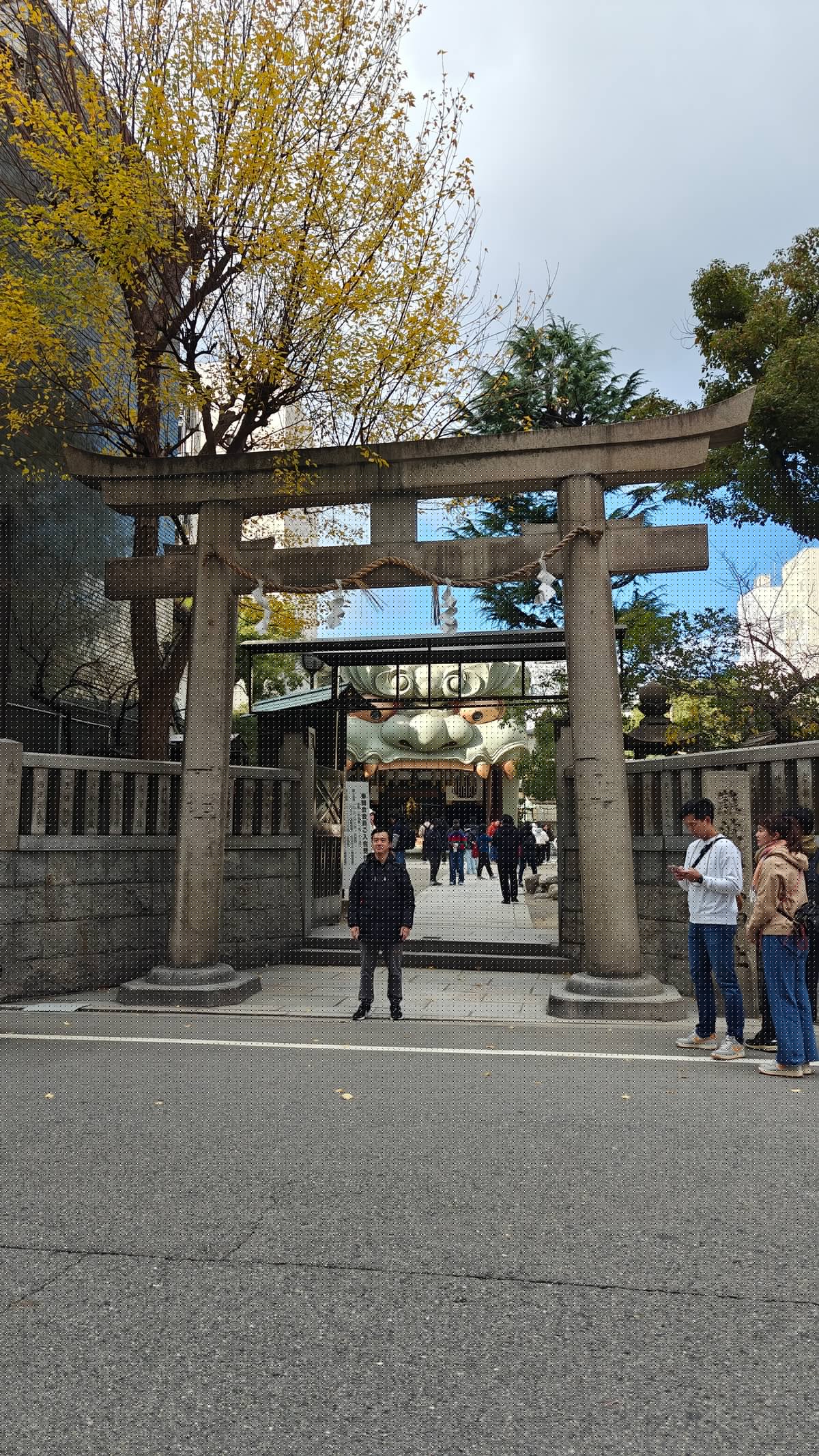 Stone torii gate entrance with person posing, autumn