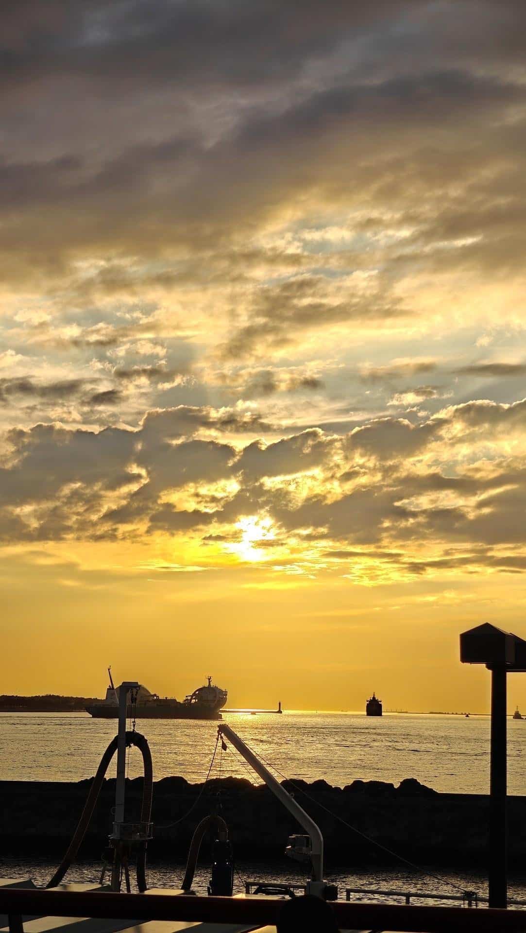 Sunset over ocean with ships and clouds