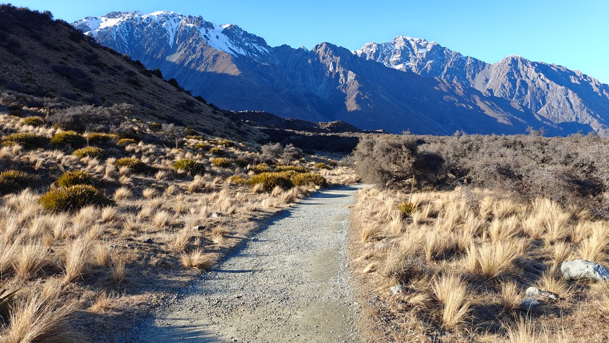 The gravel path continuing across open tussock flats