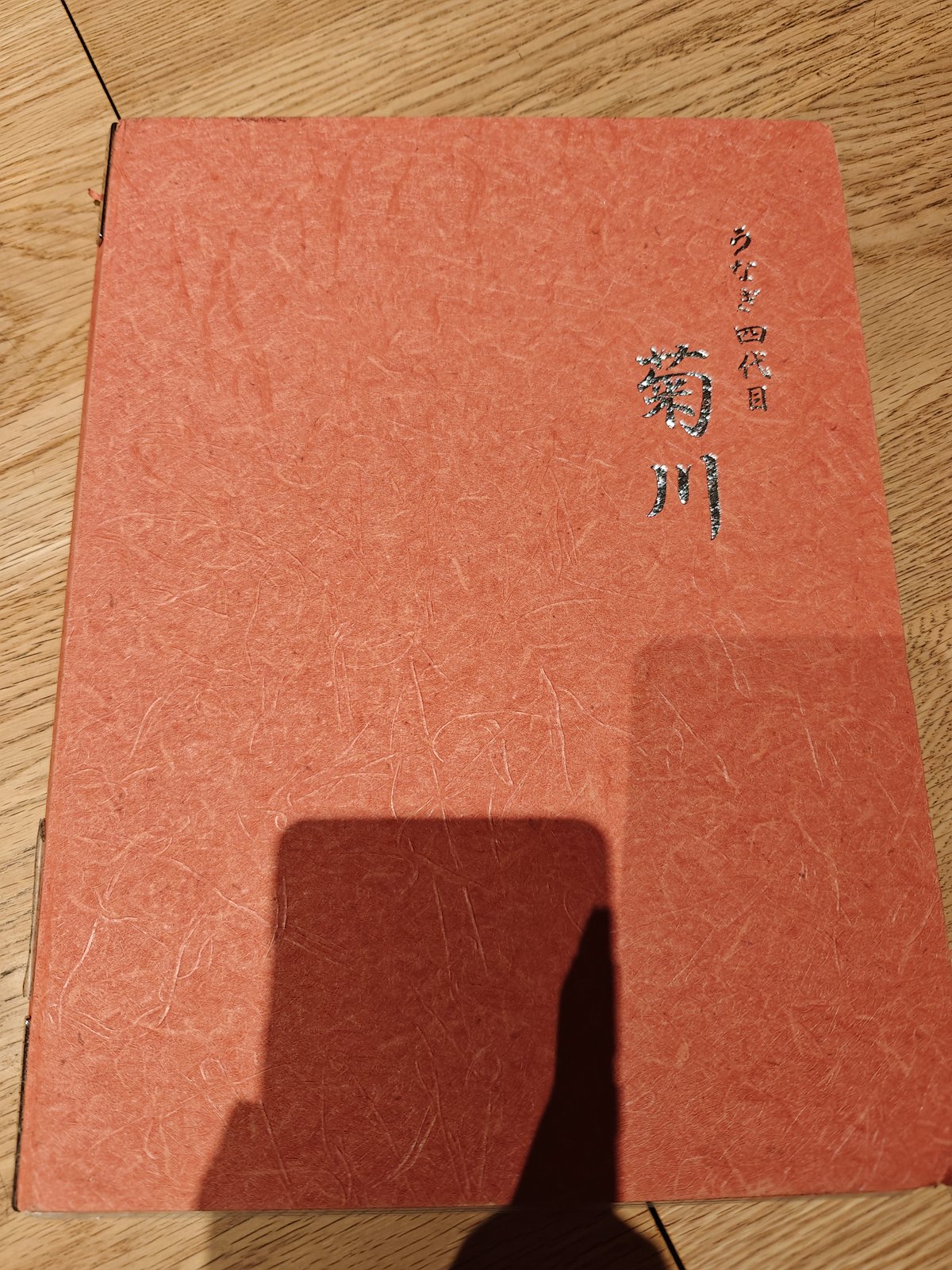 The restaurant's menu cover, a textured red-brown board