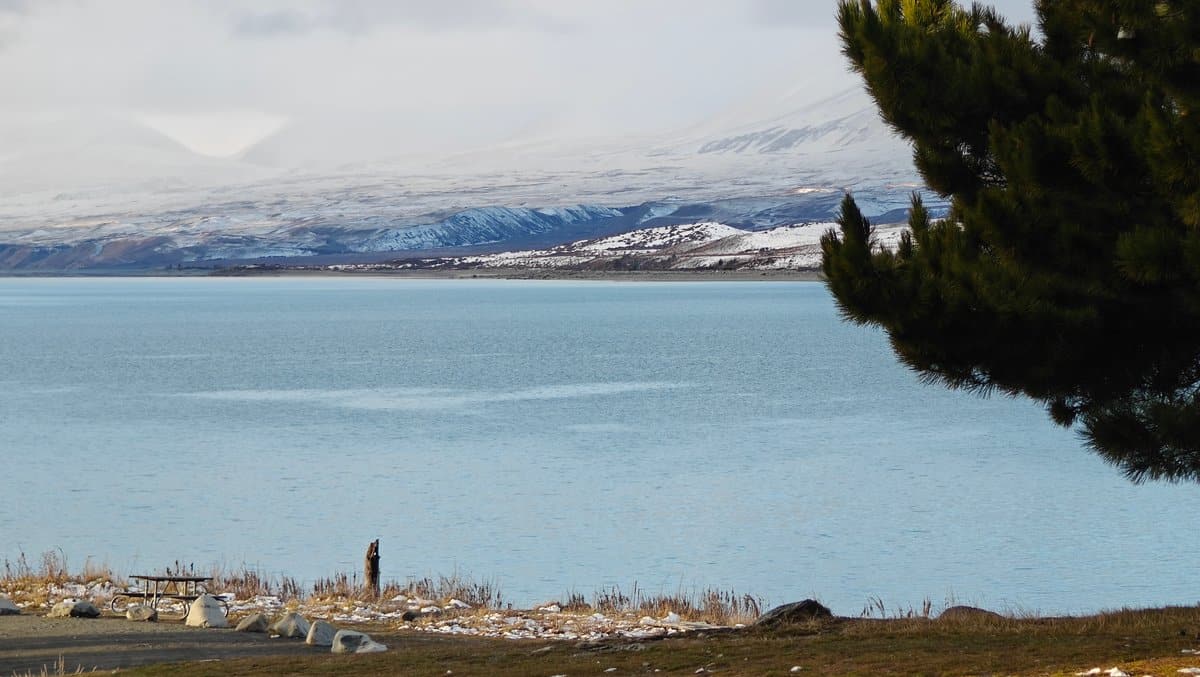 The turquoise lake meeting a stony shore dotted