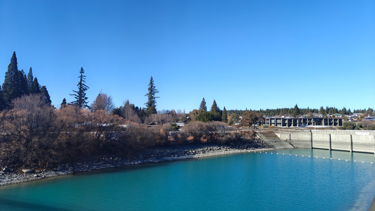 The vivid turquoise canal edged by pines and