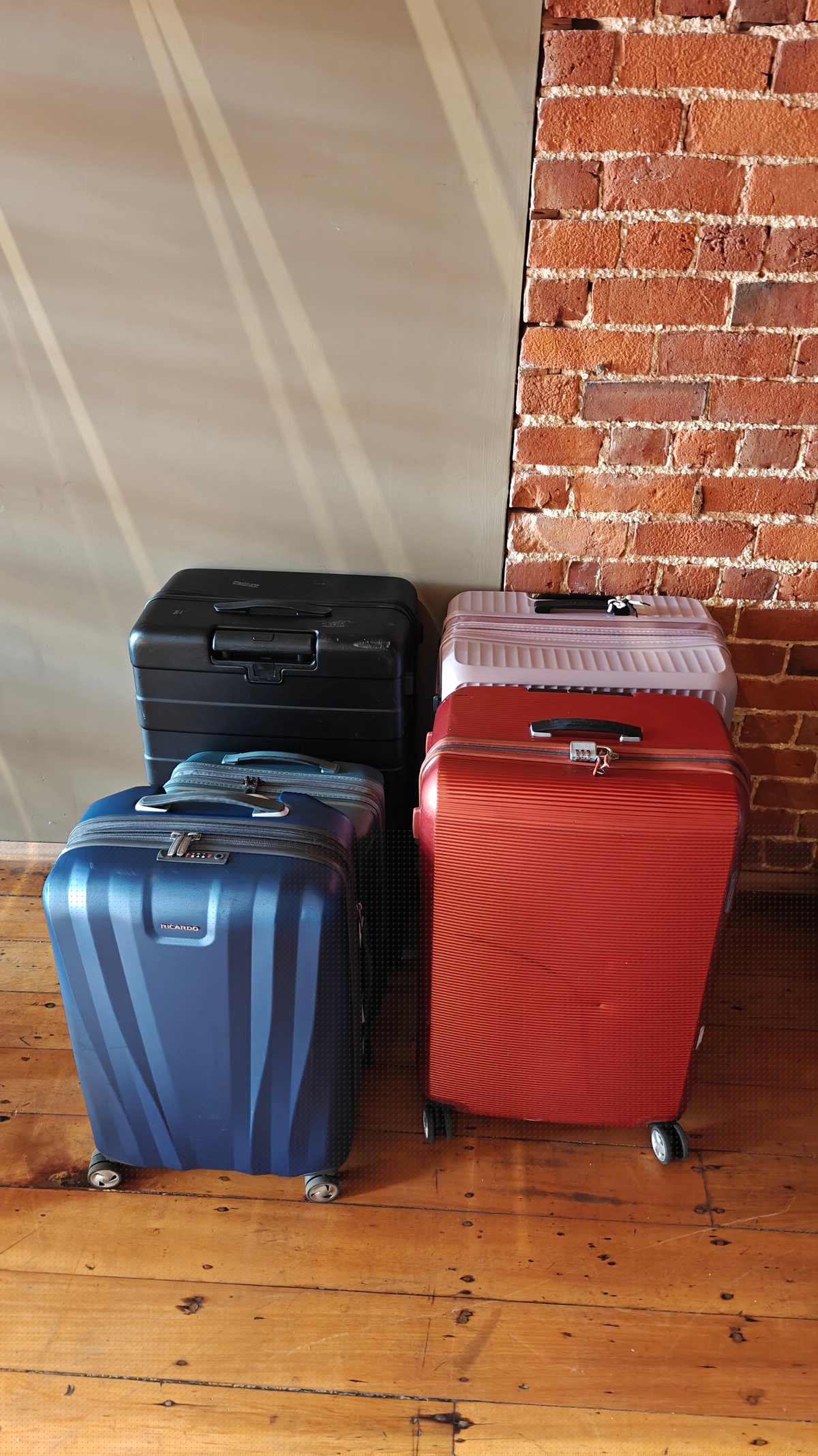 Three wheeled suitcases (blue, black and red) standing