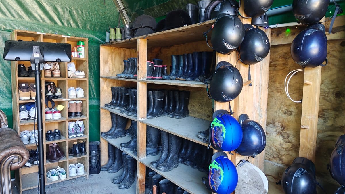 Timber shelves stacked with riding boots and rows
