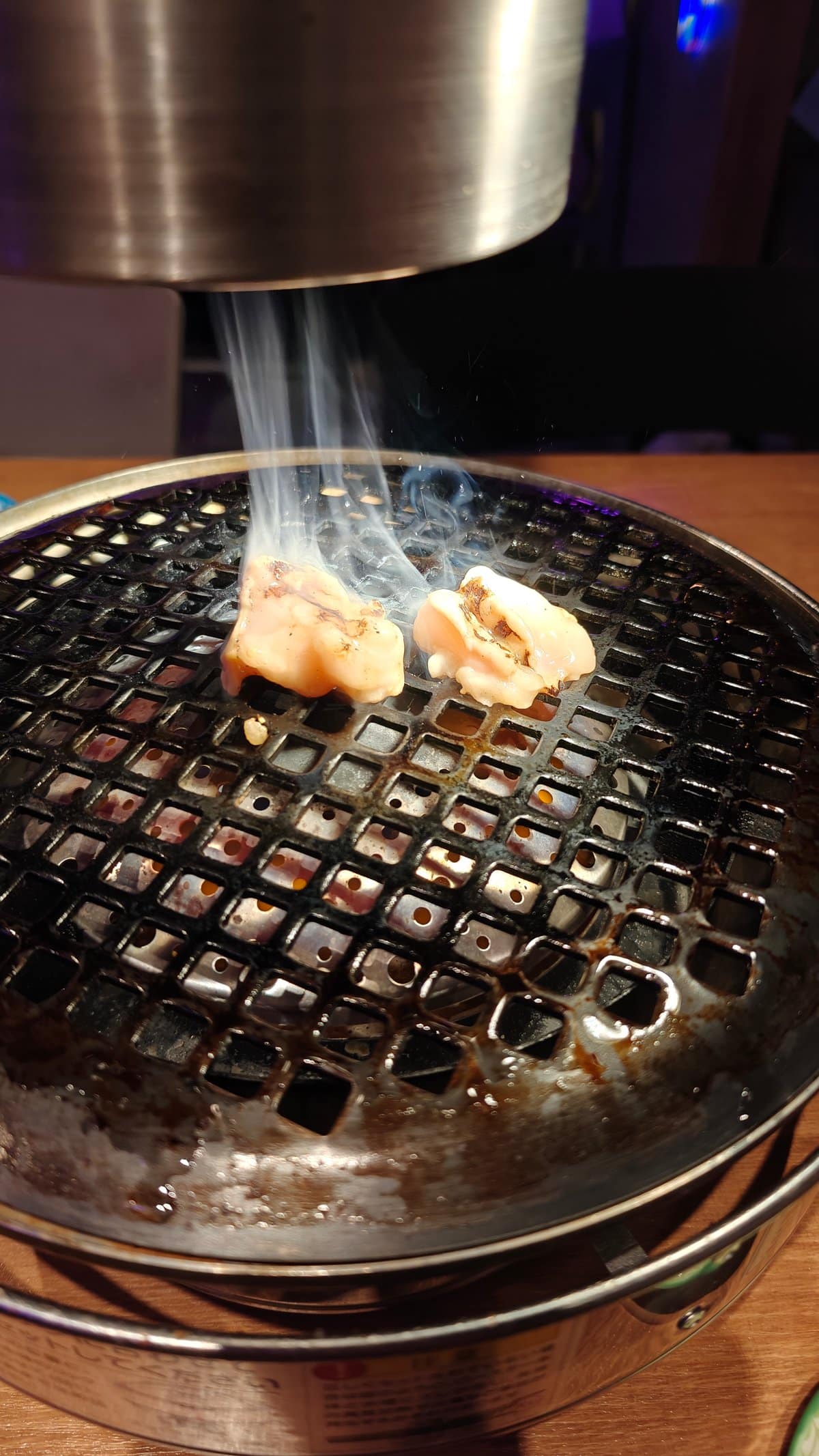 Two pieces of pale offal (marucho/ホルモン) beginning to