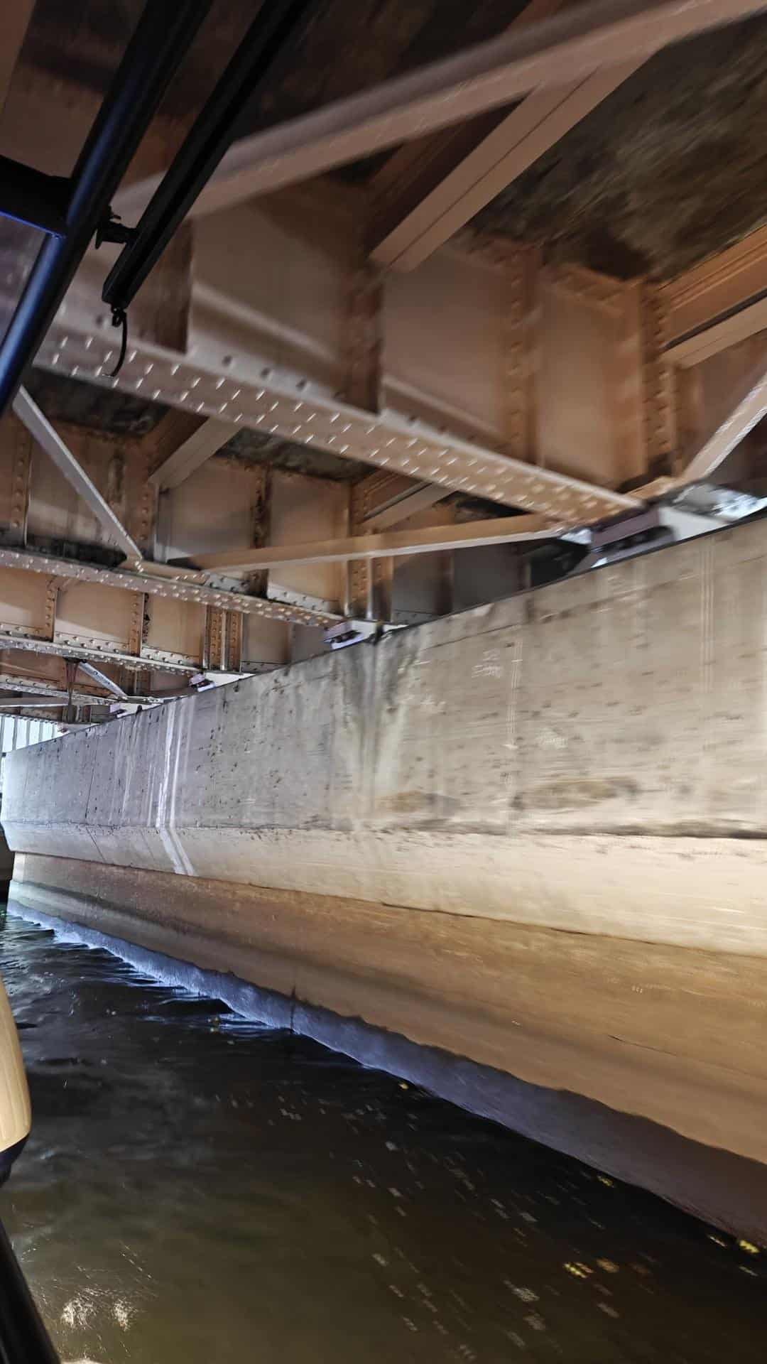 Underneath a metal bridge over water