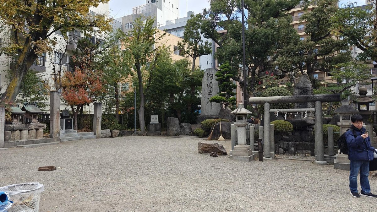 Urban shrine with stone torii and trees