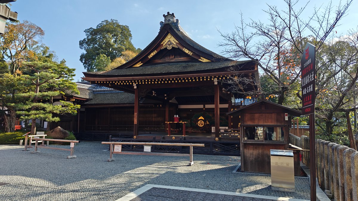 Vermilion shrine building beside a garden with trees