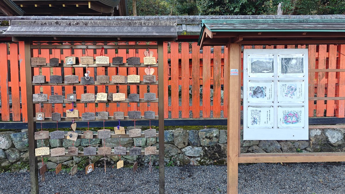 Wall of wooden ema plaques beside an information