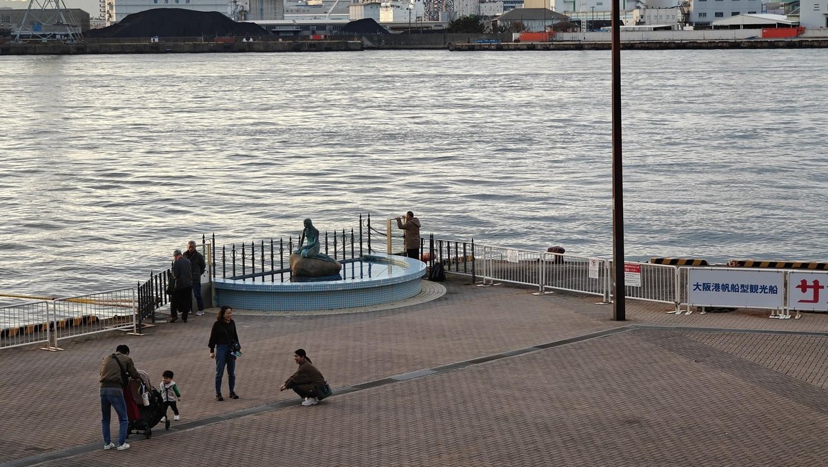 Waterfront statue with visitors nearby