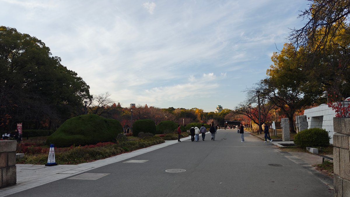Wide park path with visitors walking toward castle,