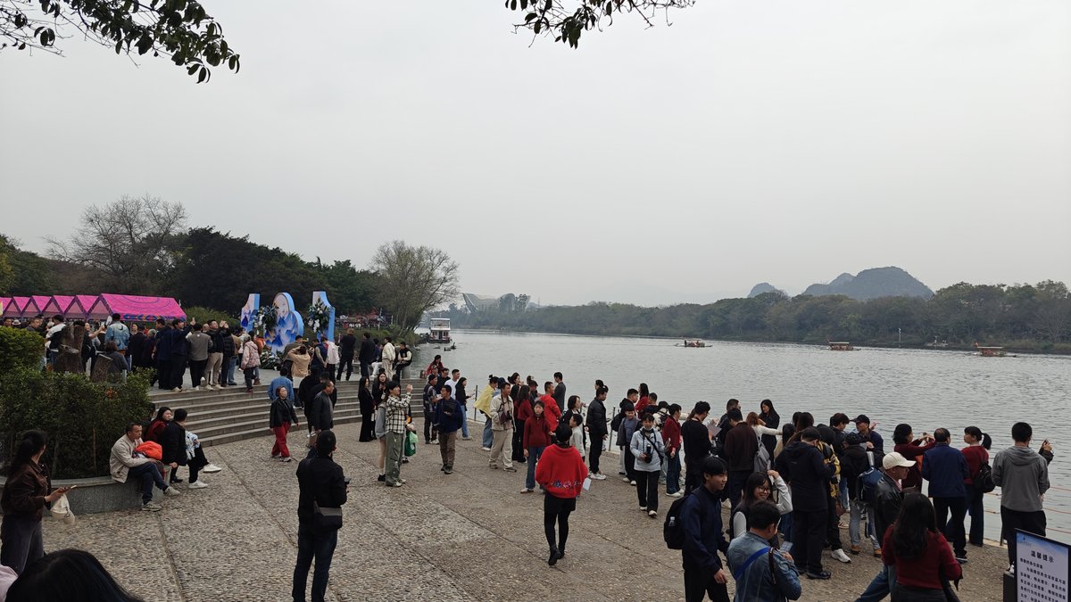 Wide riverside plaza with crowds, river, karst mountains