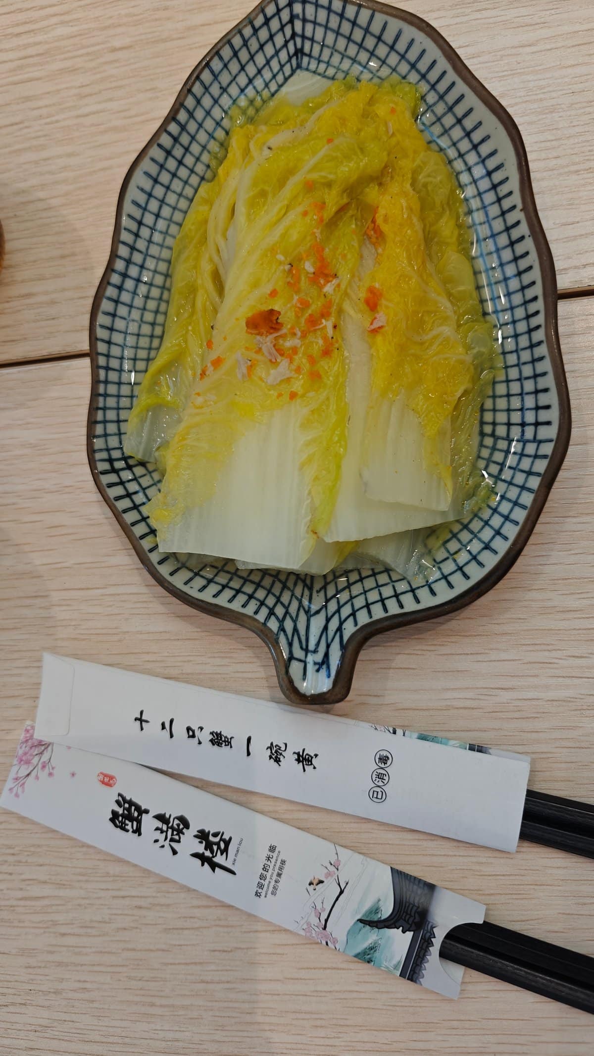 A shallow blue-patterned dish of steamed napa cabbage