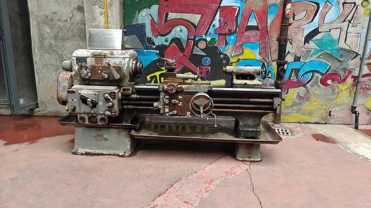 An old industrial lathe/machine displayed on a plinth