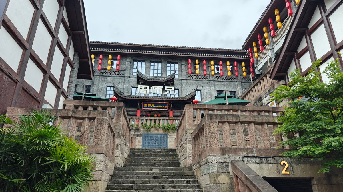 Approach to 周师兄 hot-pot restaurant — a grey-brick,