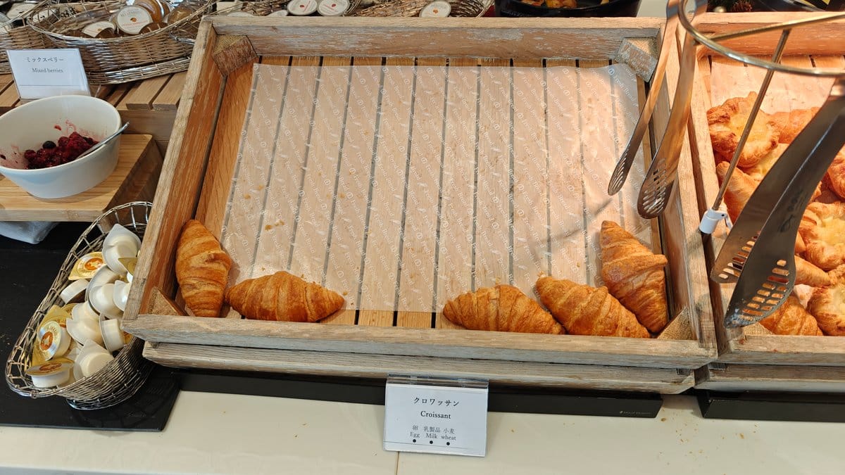 Basket of croissants and rolls with stacked plates