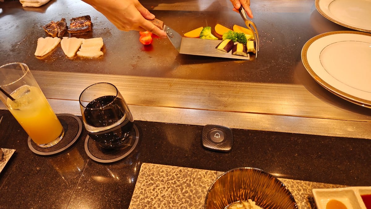 Chef cooking vegetables and tofu on teppan with