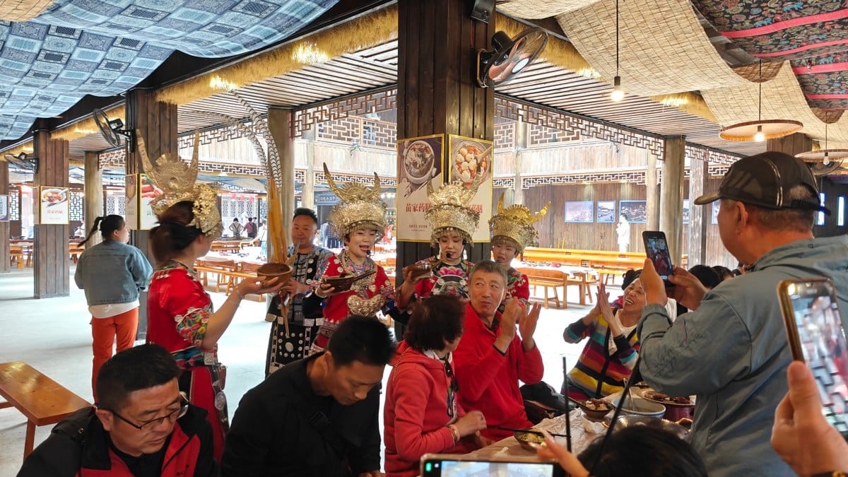 Guests, some in red Miao dress, gathered and