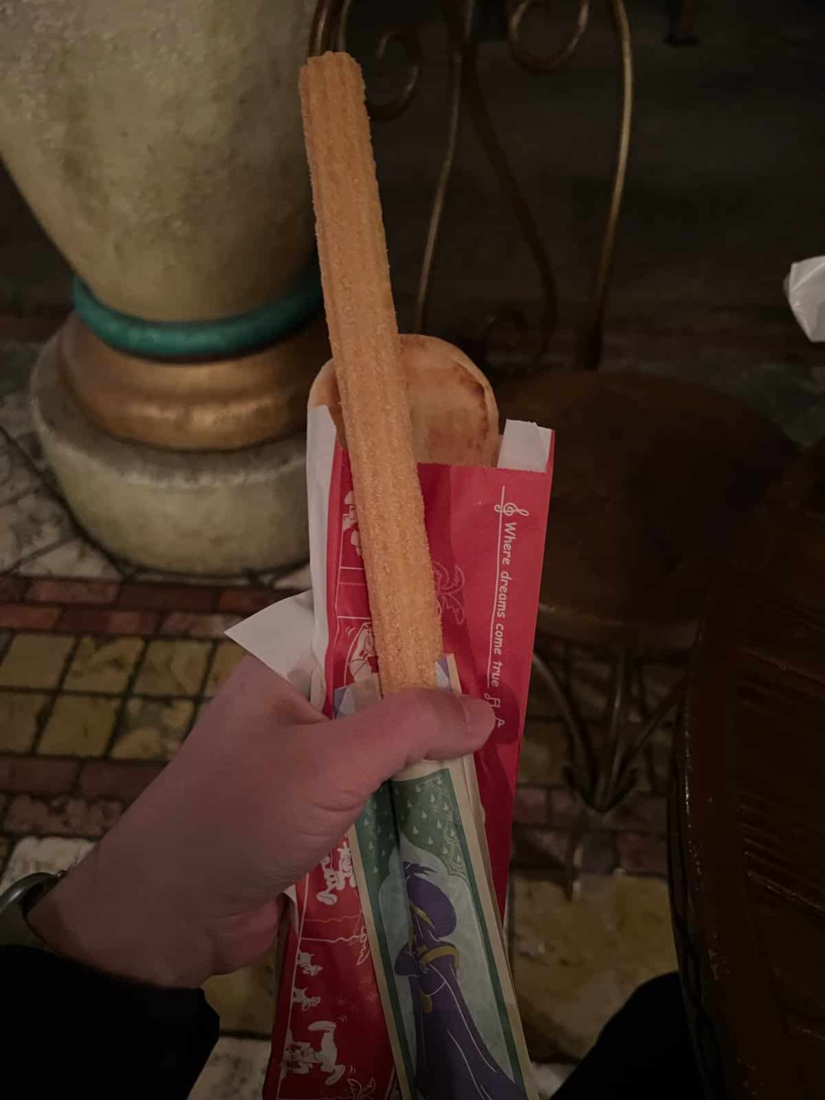 Hand holding a churro in a red DisneySea