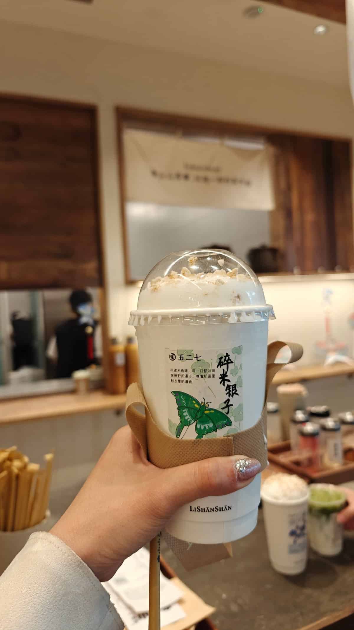 Hand holding a domed clear cup of milk-rice