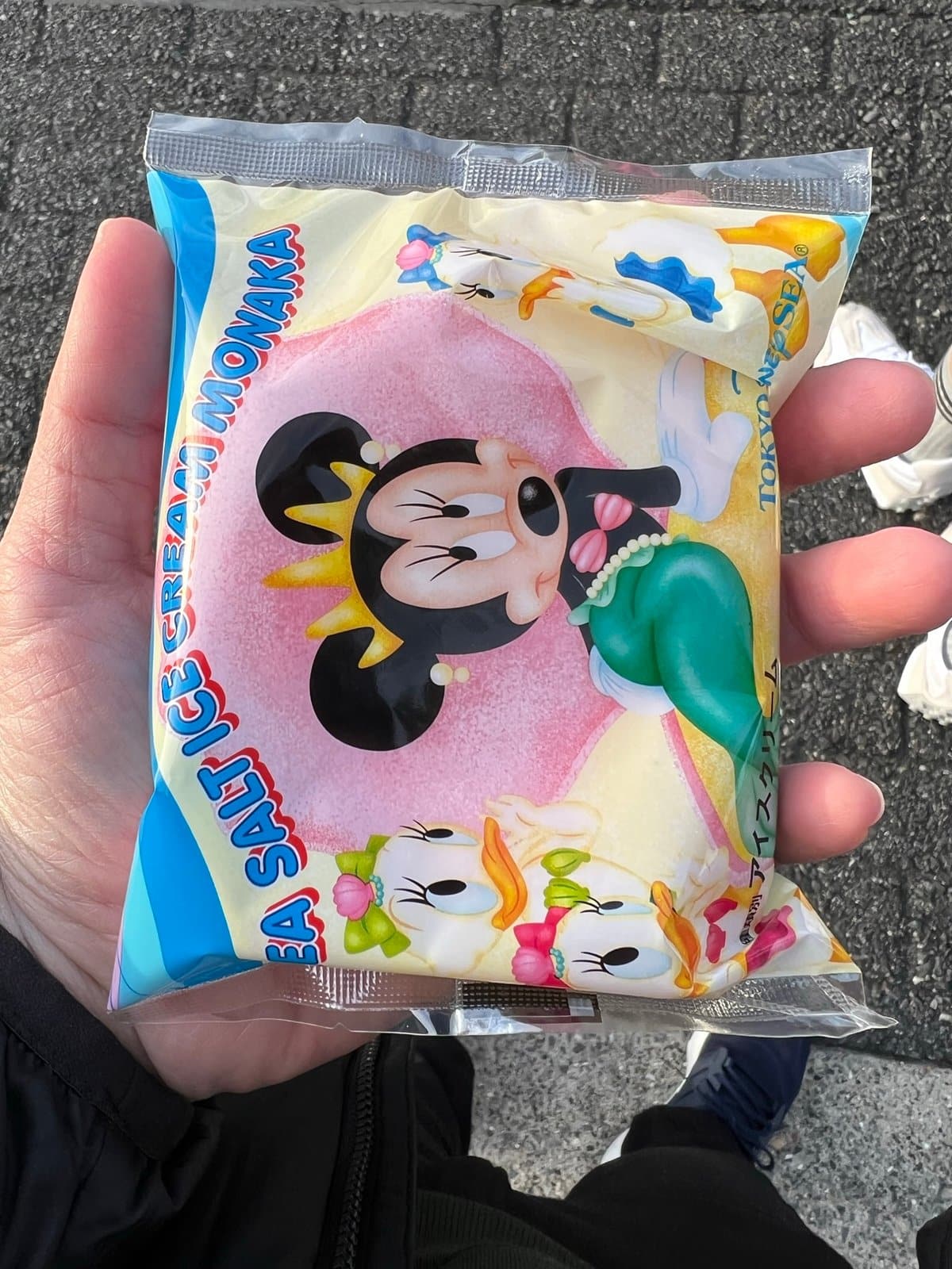 Hand holding a pink souvenir snack pouch printed