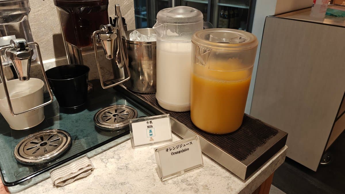 Milk and orange juice dispensers beside the coffee