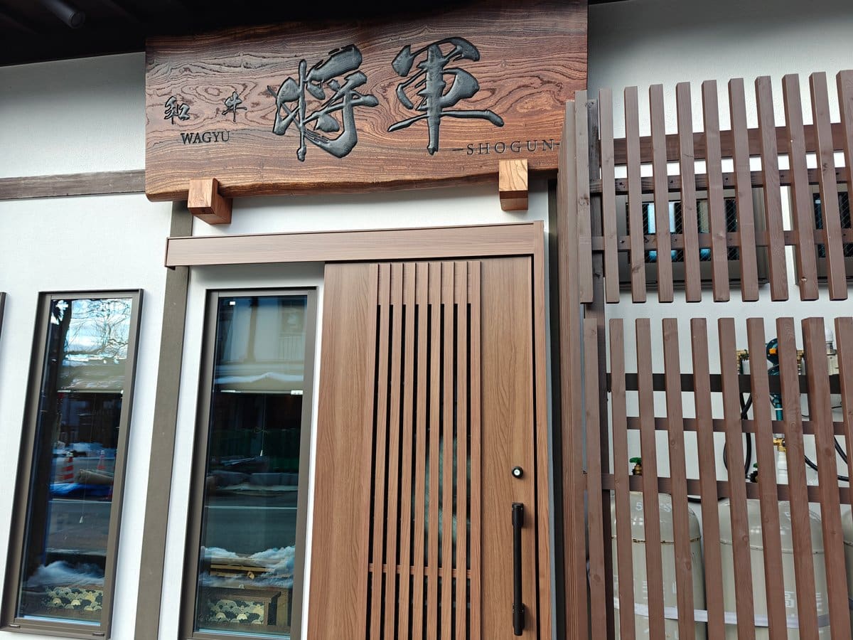 Modern wood-slatted shopfront with a carved sign reading