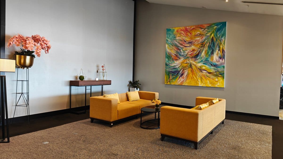 Mustard-yellow sofa seating nook beneath the large colourful