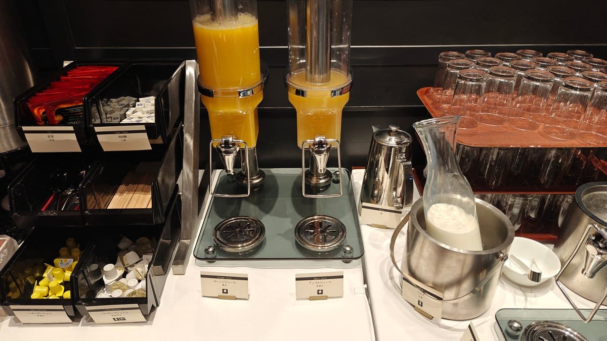 Orange juice dispensers and glasses at the buffet