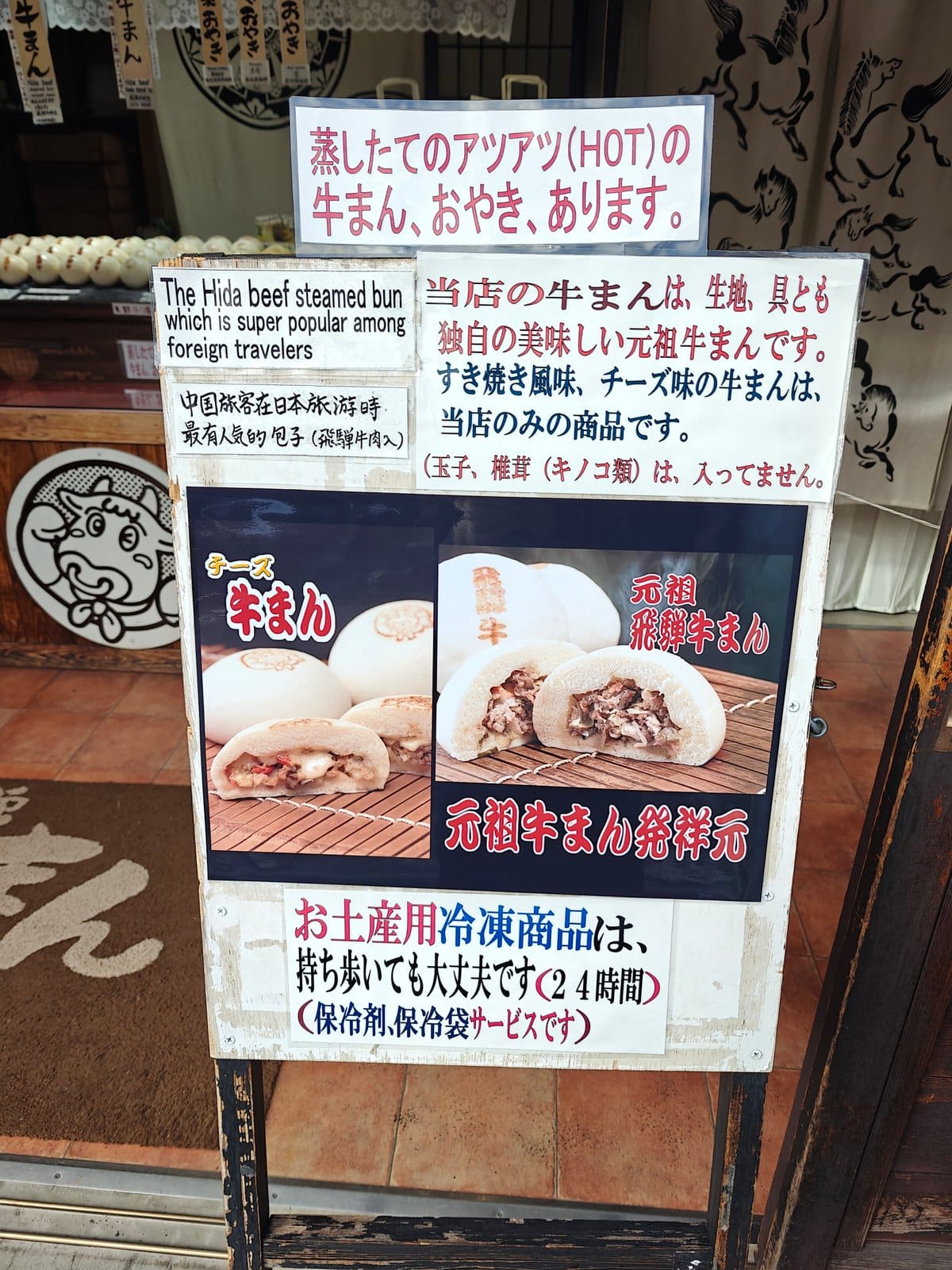 The shop's info/menu A-frame: 蒸したてのアツアツ(HOT)の牛まん、おやき、あります。; a note that
