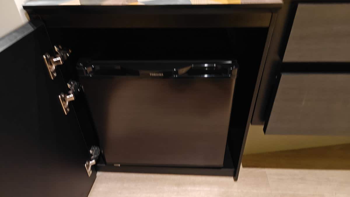 Toshiba mini-fridge inside dark wood cabinet