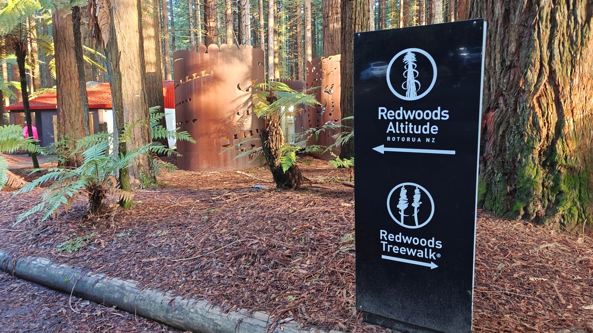 A black signpost with arrows to Redwoods Altitude