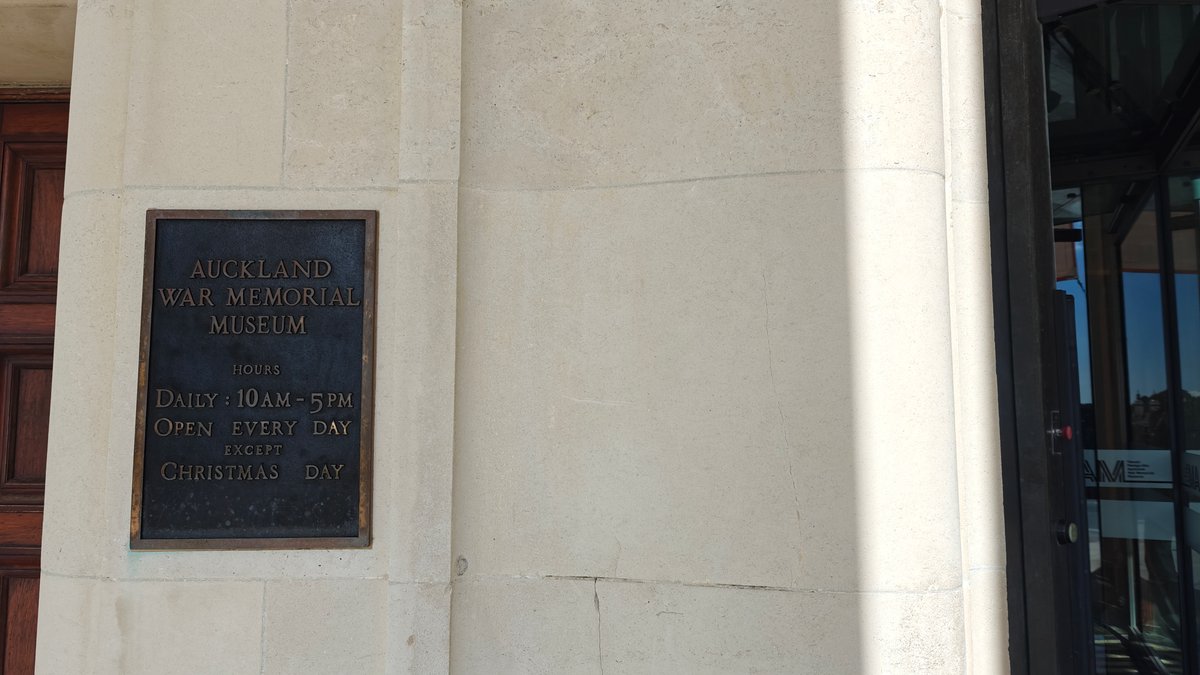 A bronze plaque giving the museum opening hours.