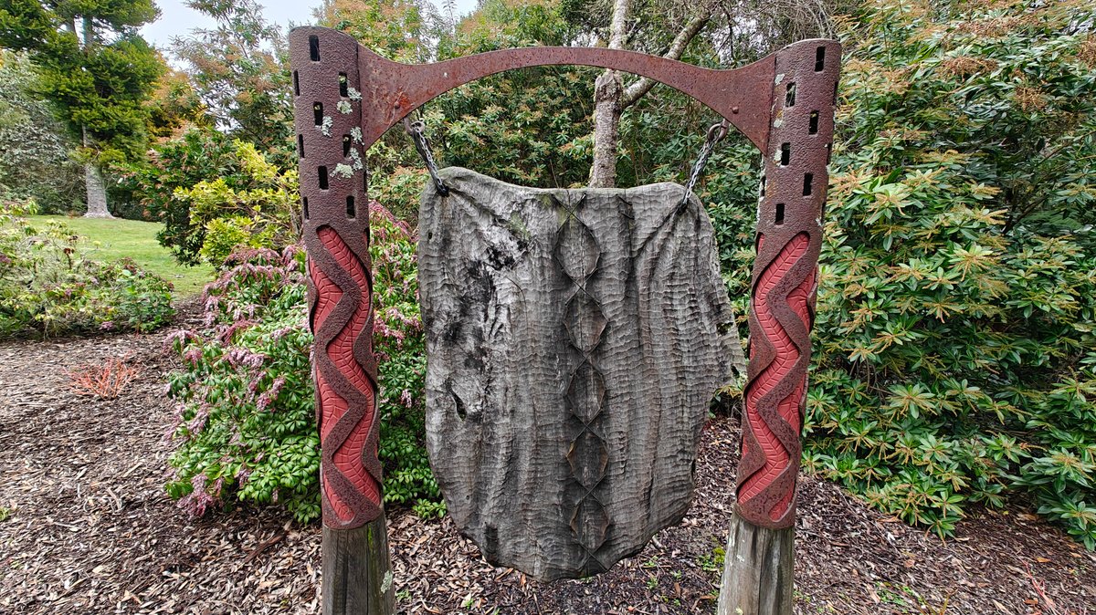 A carved timber panel standing in the garden.