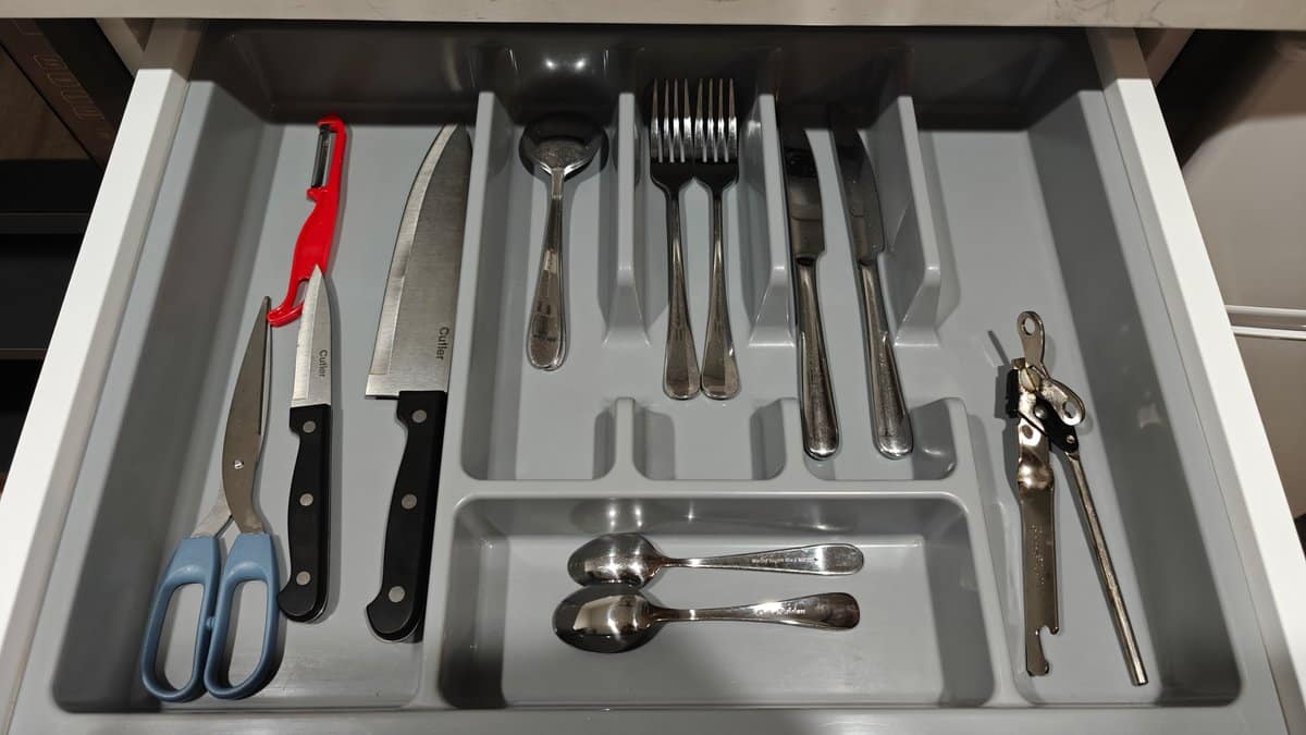 A drawer of cutlery with knives, scissors and