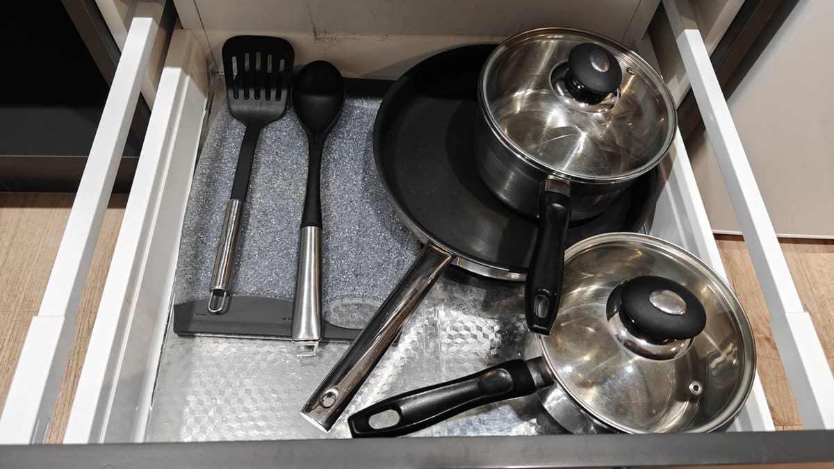 A drawer with pans, a chopping board and