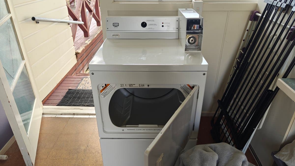 A dryer with drying racks stacked beside it.