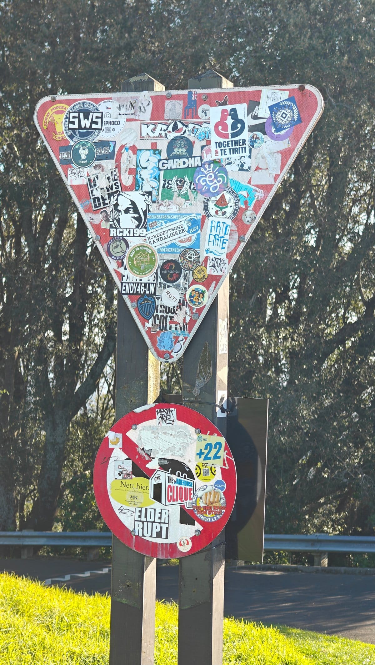 A give-way sign post plastered with stickers at
