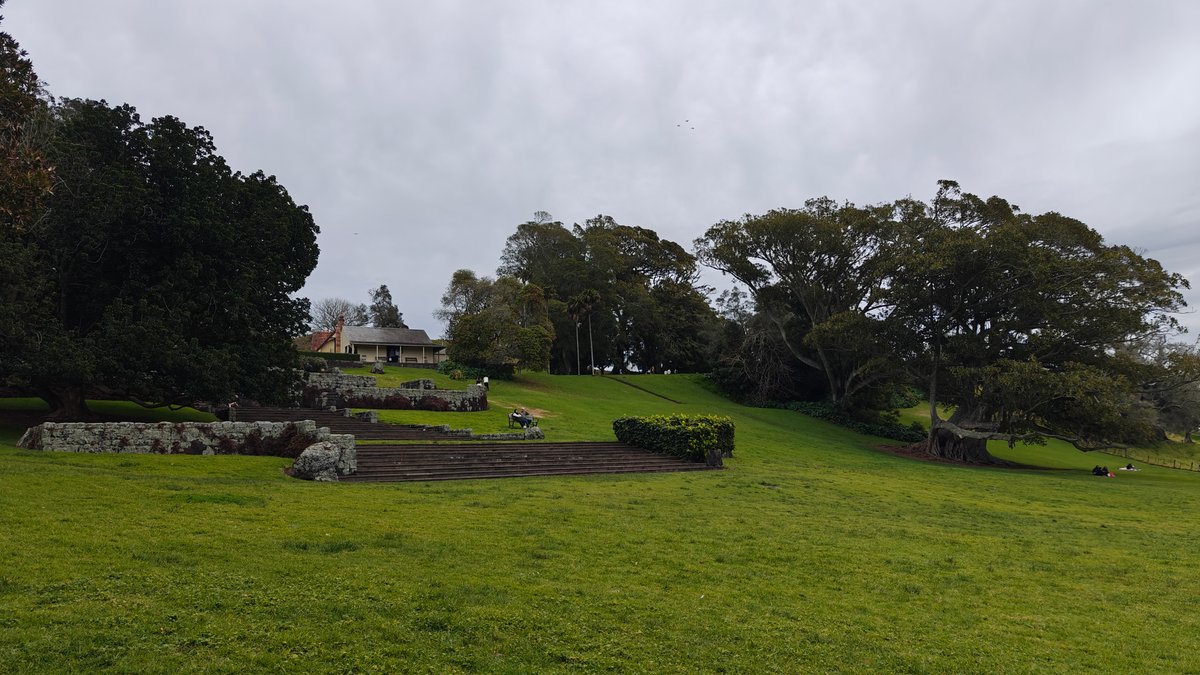 A grassy slope with trees and stonework set