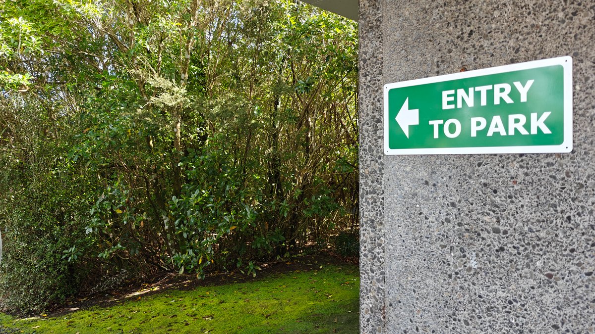A green ENTRY TO PARK arrow sign set