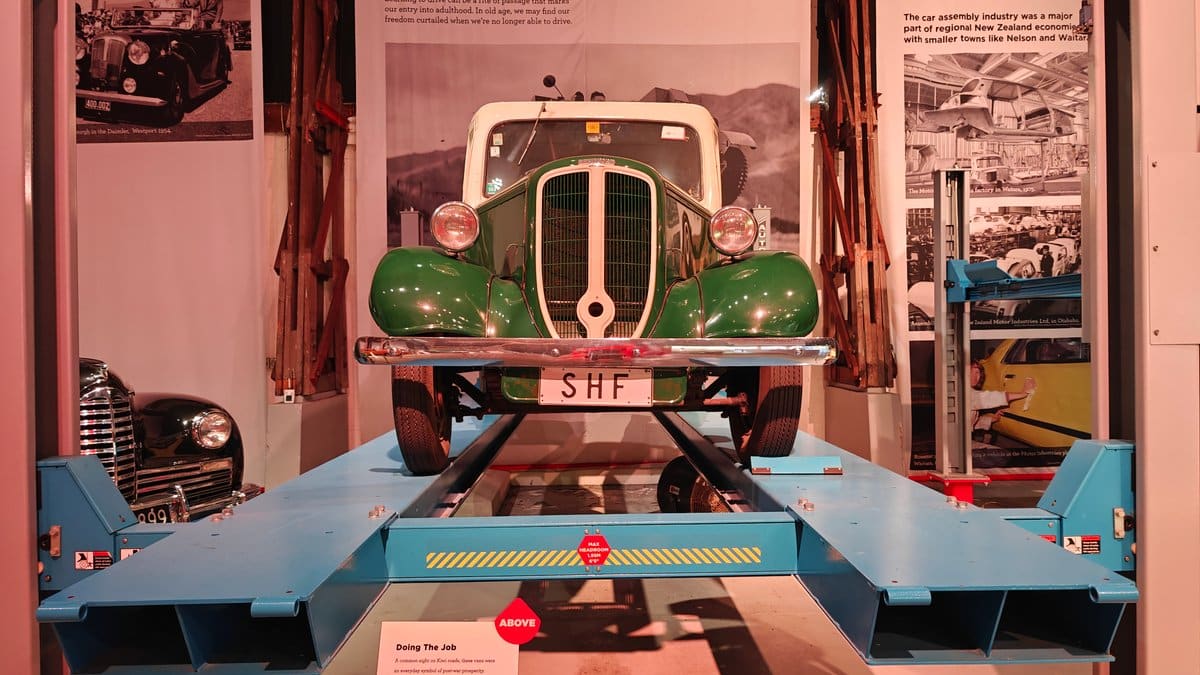A green vintage vehicle raised on a blue
