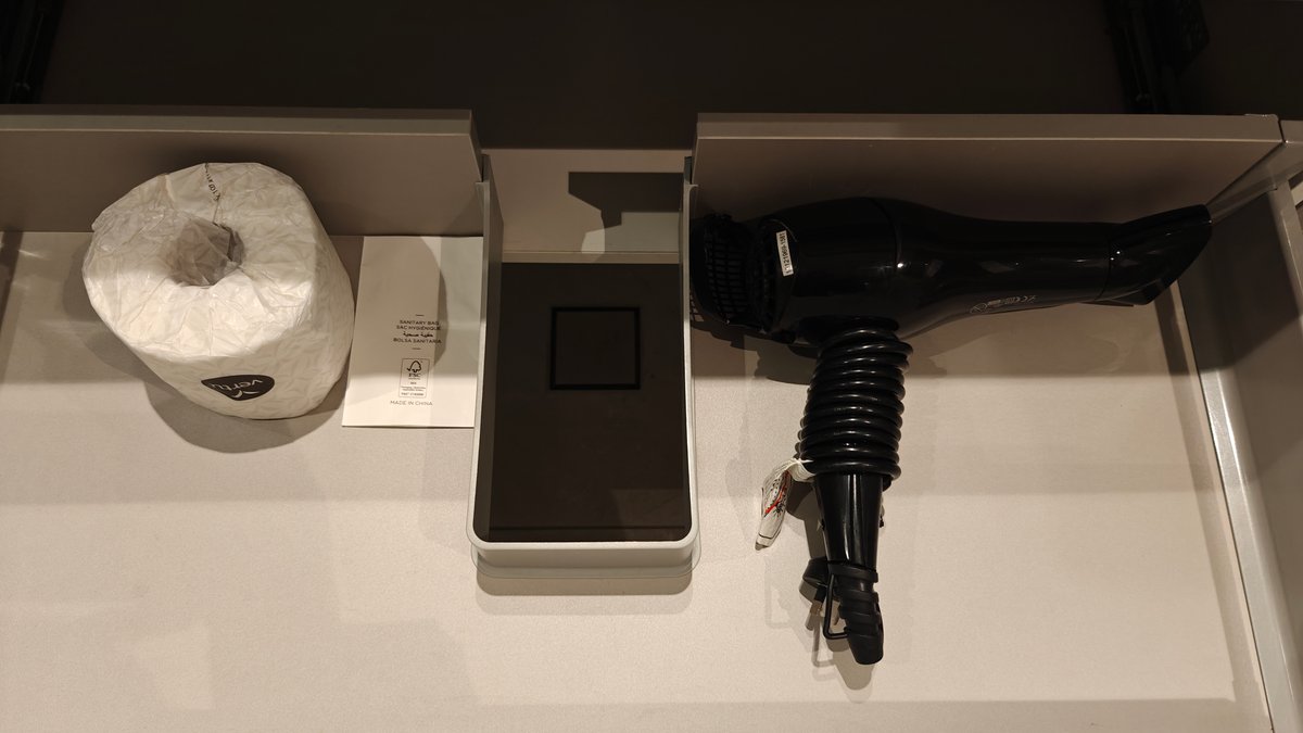 A hairdryer and spare toilet roll in the
