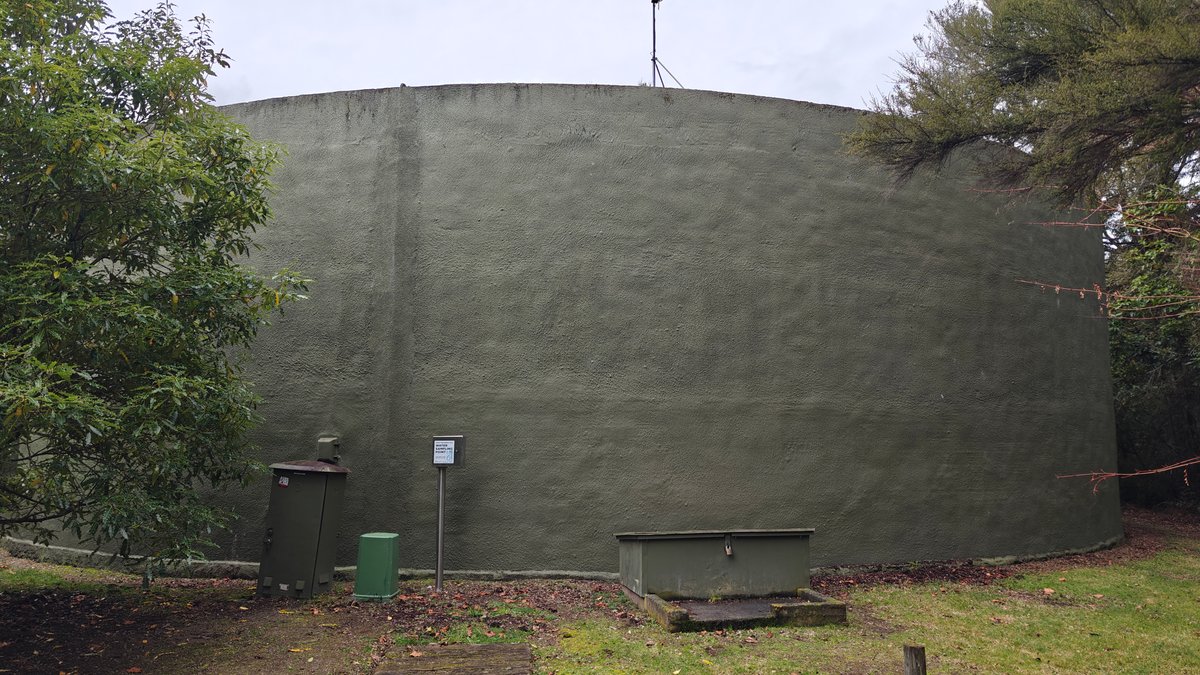 A large green concrete water reservoir tank standing