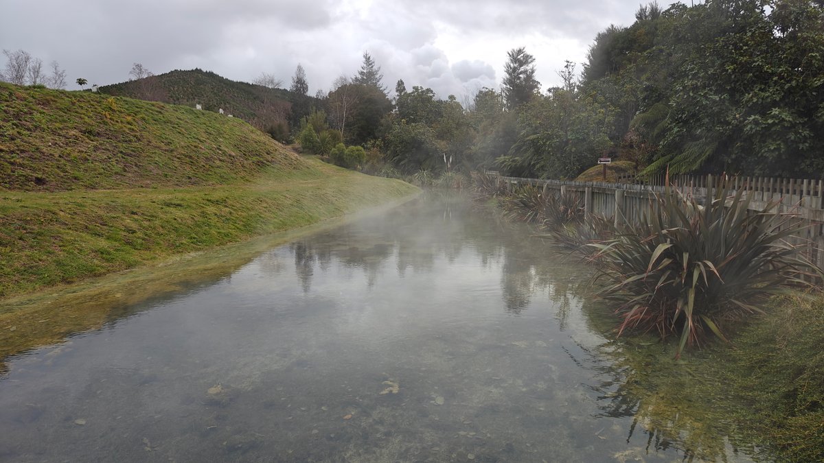 A pool with grassy banks and steam lifting