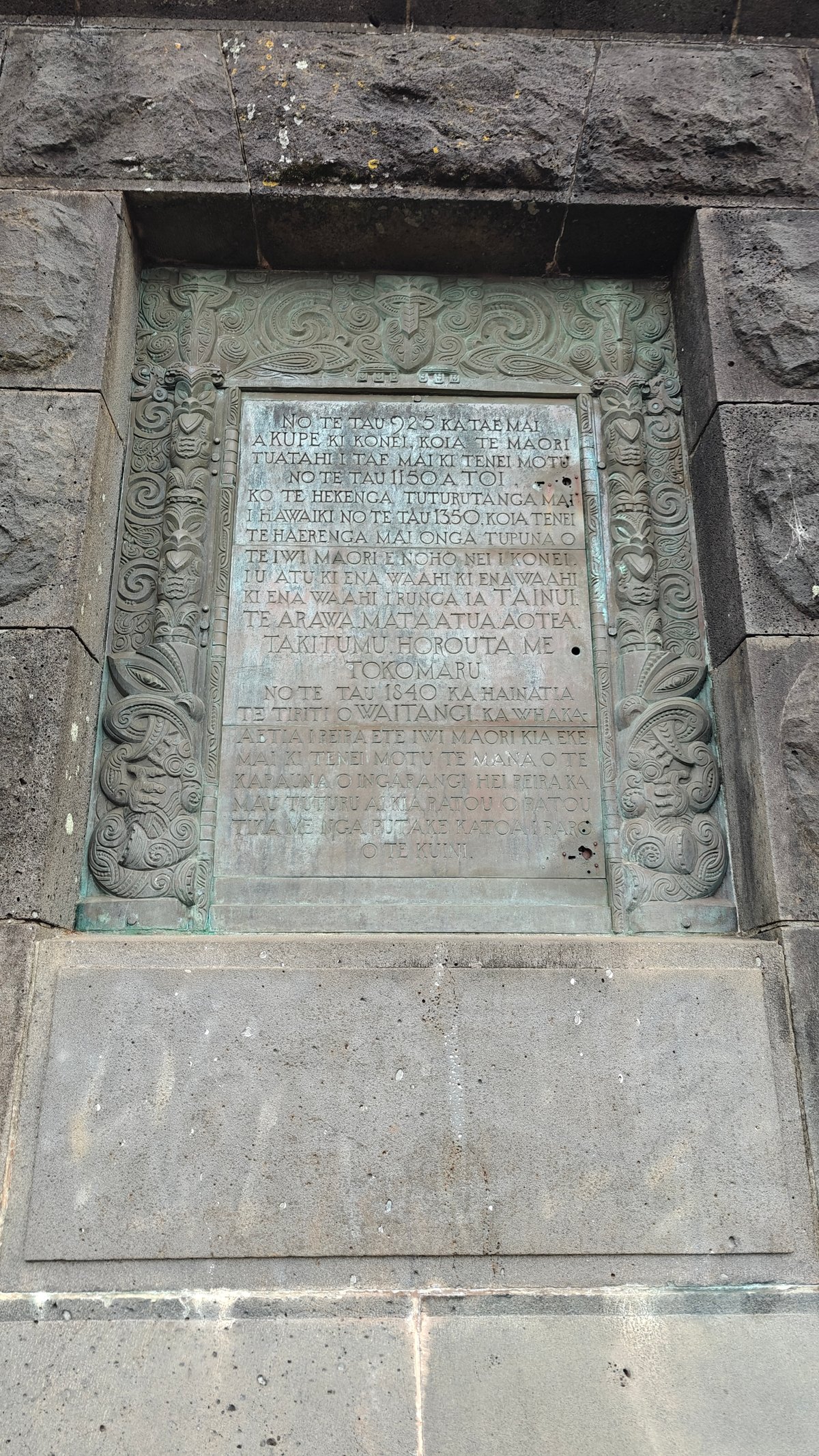 A second bronze plaque, its inscription weathered green